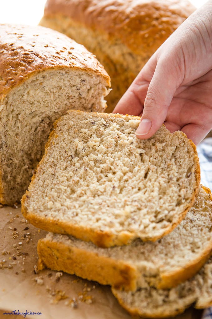 closeup image: hand reaching for a slice of whole grain bread