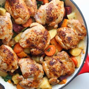 paprika chicken thighs in a pan with roasted root vegetables