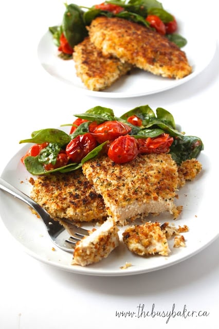 Italian Chicken Milanese on a plate with oven roasted tomatoes and spinach