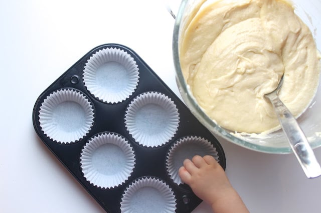 cupcake pan lined with paper cupcake liners next to a bowl of cupcake batter