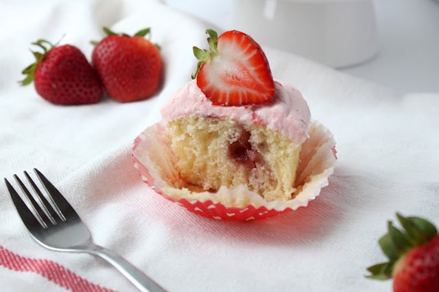 Strawberry Cupcakes with Fresh Strawberry Buttercream are the perfect summer dessert, packed with fresh strawberries. You'll love this easy cupcakes recipe! #cupcakes #recipe #strawberries #desserts a strawberry cupcake cut in half, revealing the moist cupcake crumb