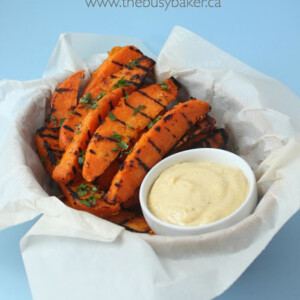 wedges of grilled sweet potatoes in a basket with curry aioli for dipping.