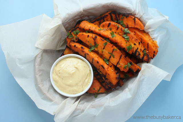 basket of grilled sweet potatoes cut into wedges, garnished with fresh herbs