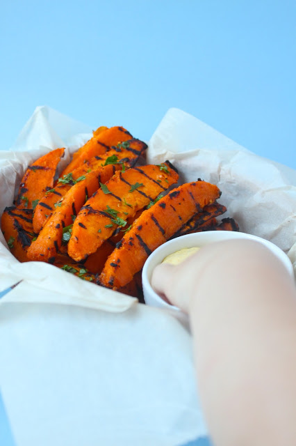 hand dipping grilled sweet potato wedges into dipping sauce