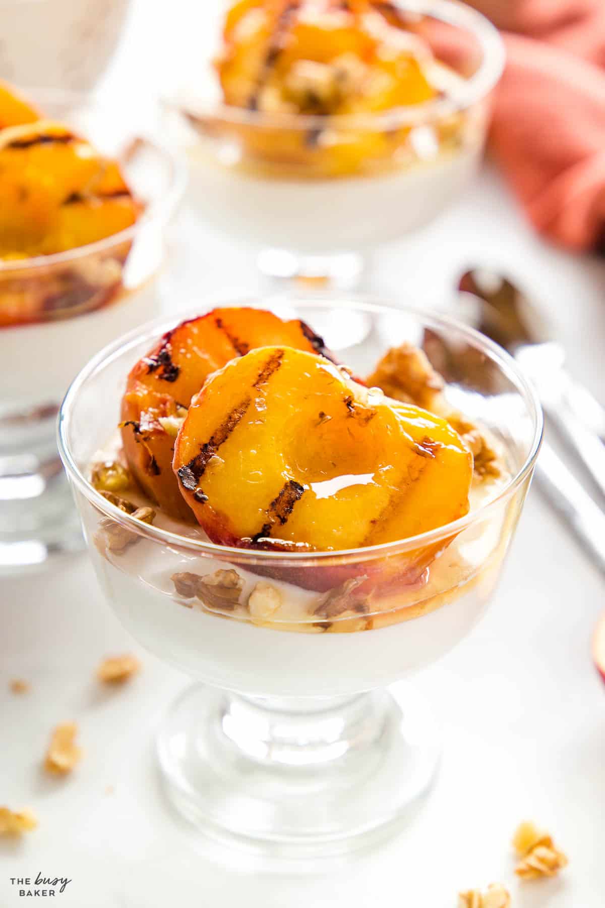 grilled peaches in a glass bowl with yogurt and honey and walnuts