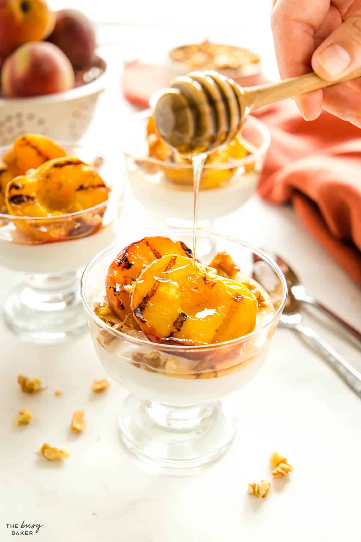 honey being poured on grilled peaches with yogurt and walnuts