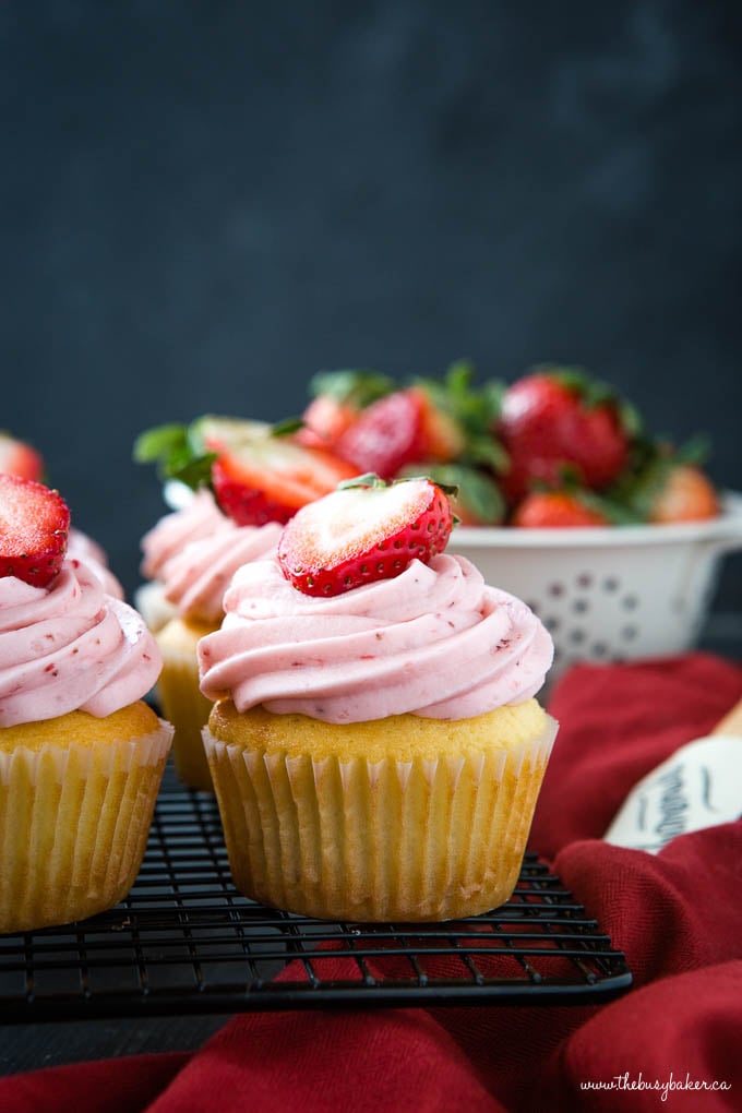 juicy strawberry frosting on top of a white cupcake