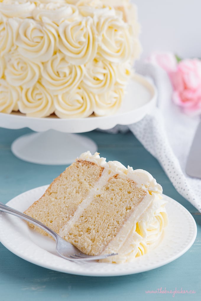 Best Ever Vanilla Bean White Cake slice on plate with fork and flowers