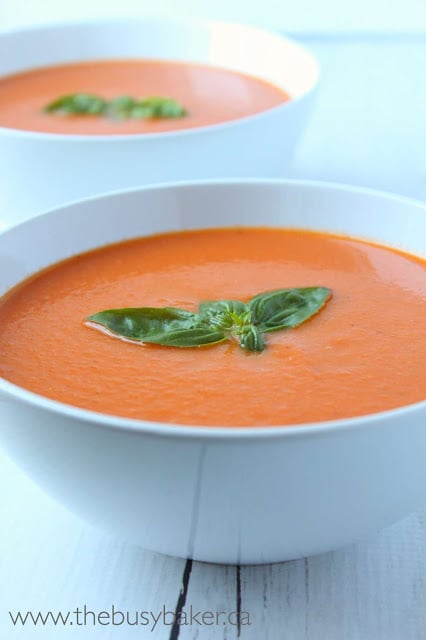 2 bowls of creamy tomato soup topped with fresh basil