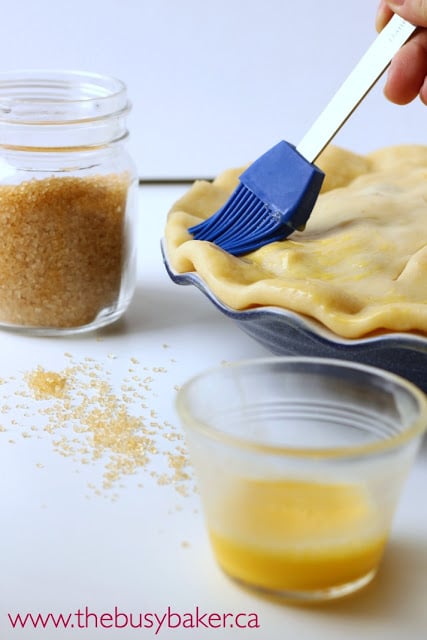 brushing egg wash over an unbaked pie crust