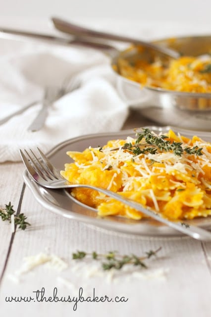 plate of pasta covered with butternut squash pasta sauce, parmesan cheese and sprigs of thyme