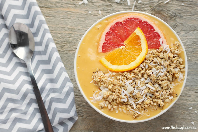 healthy breakfast smoothie bowl topped with citrus slices, granola and shredded coconut