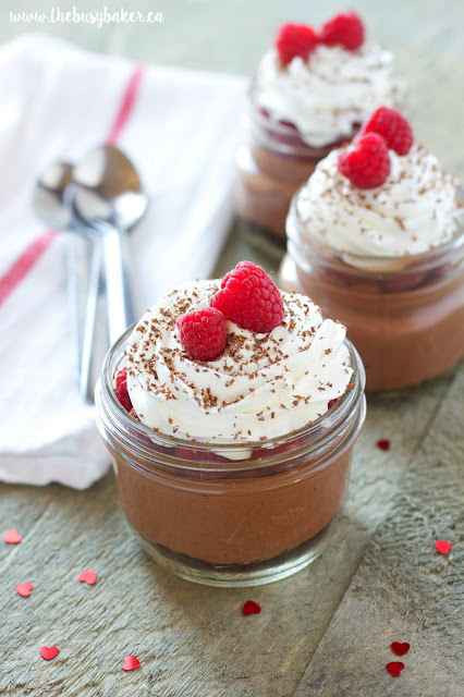 low fat and low sugar mason jar cheesecakes topped with fresh raspberries, chocolate and whipped cream
