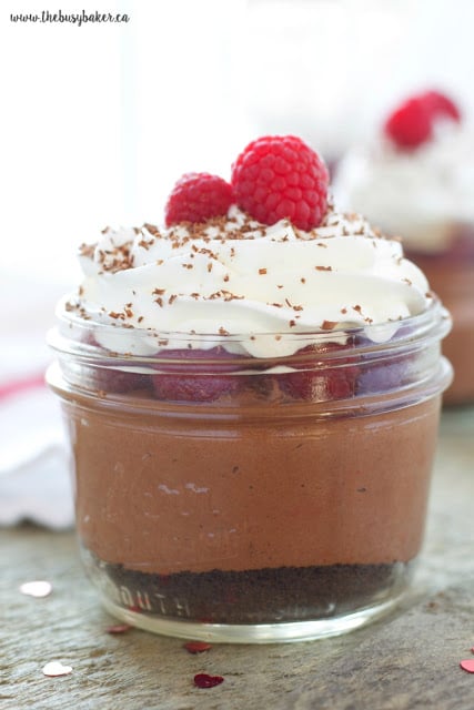 single serve chocolate no bake cheesecake topped with whipped cream and fresh raspberries
