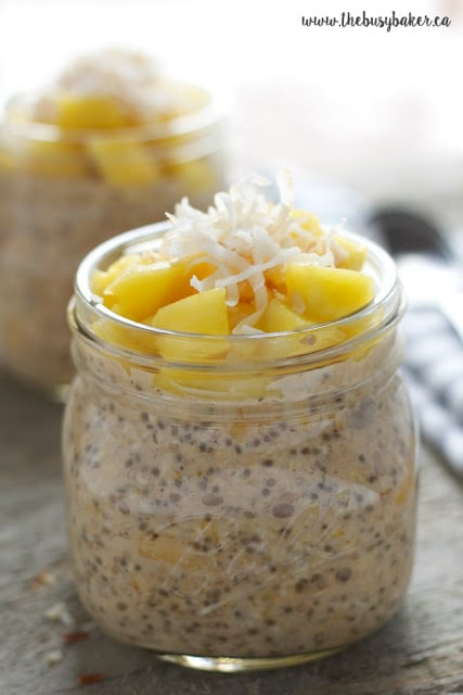 jar of coconut overnight oats topped with chunks of mango and shredded coconut