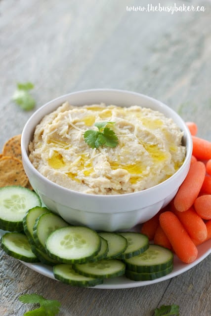 bowl of garlic white bean hummus with raw veggies for dipping