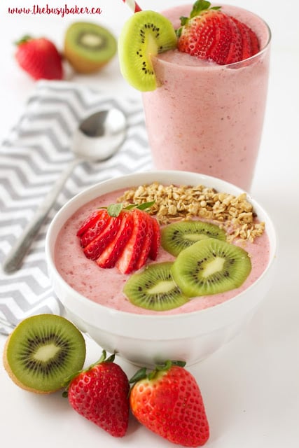 strawberry smoothie in a bowl with sliced strawberries, kiwi fruit and granola on top