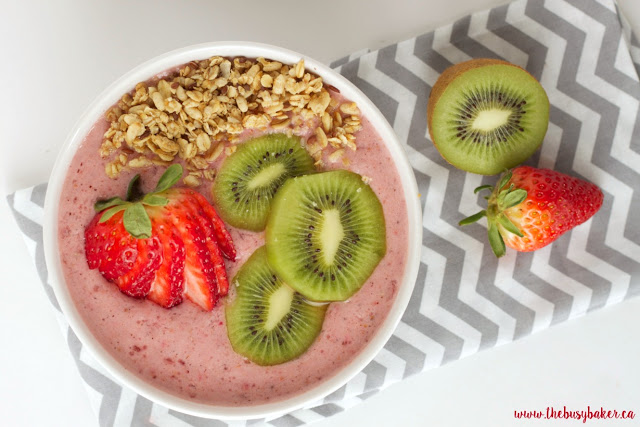 strawberry kiwi smoothie bowl topped with sliced fruit and granola