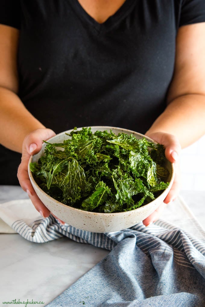 hands holding bowl of kale chips