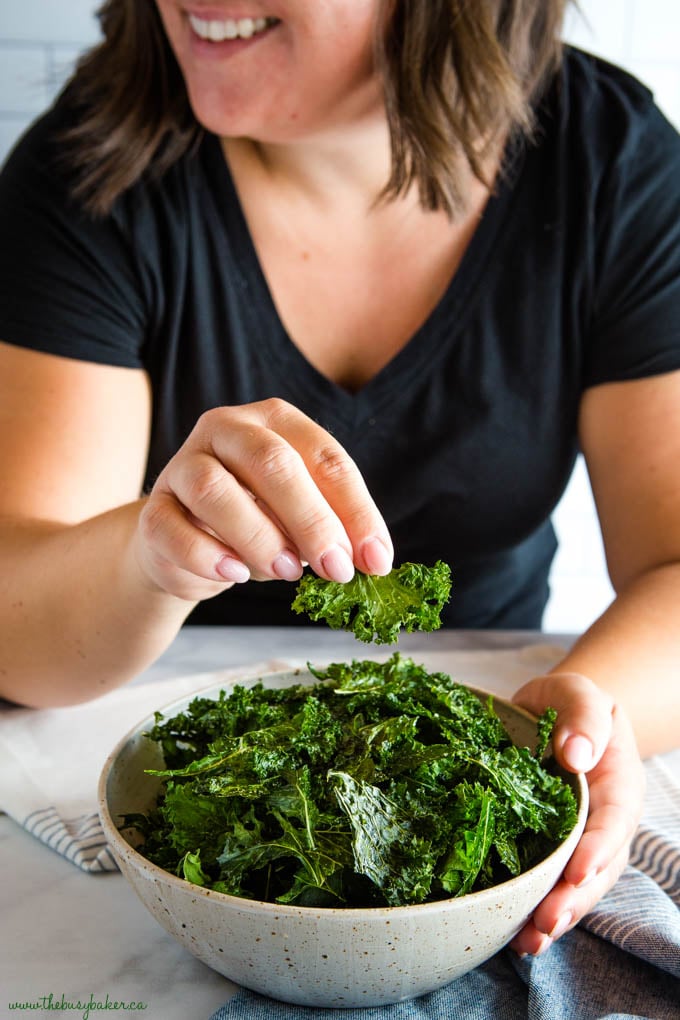 No fail, crispy kale chips every time! Sea Salt and Garlic Kale Chips recipe from thebusybaker.ca girl enjoying Kale Chips