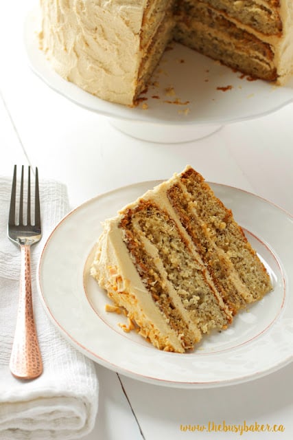 dessert plate holding a slice of banana layer cake with fluffy peanut butter frosting