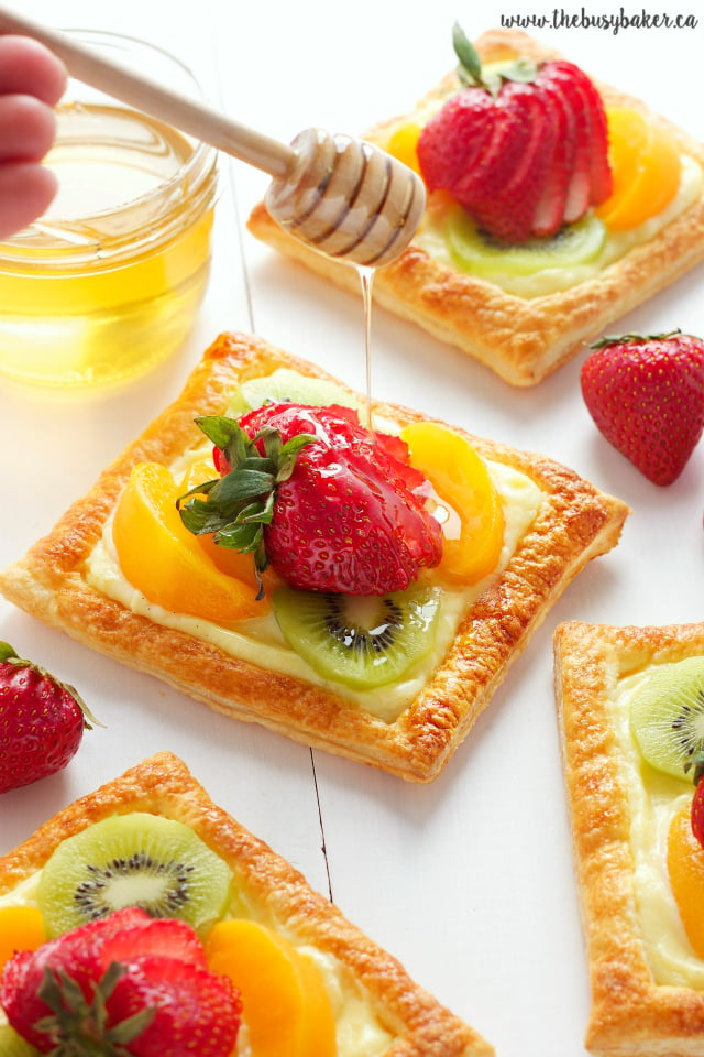 honey being drizzled over individual fresh fruit tarts