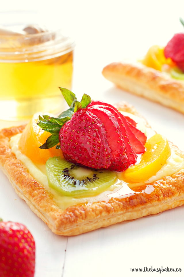 close up image of a vanilla bean custard fruit tart with honey glazed fruit on top