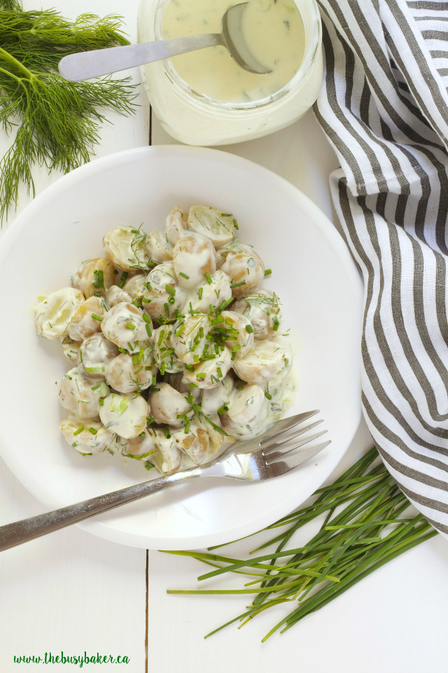 bowl of Healthy Buttermilk Ranch Potato Salad surrounded by fresh dill and chives