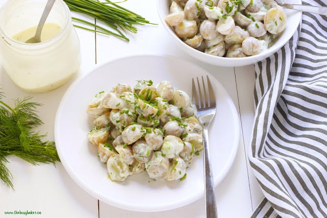 overhead image of Healthy Buttermilk Ranch Potato Salad on a plate. A bowl of the potato salad sits above it in the photo