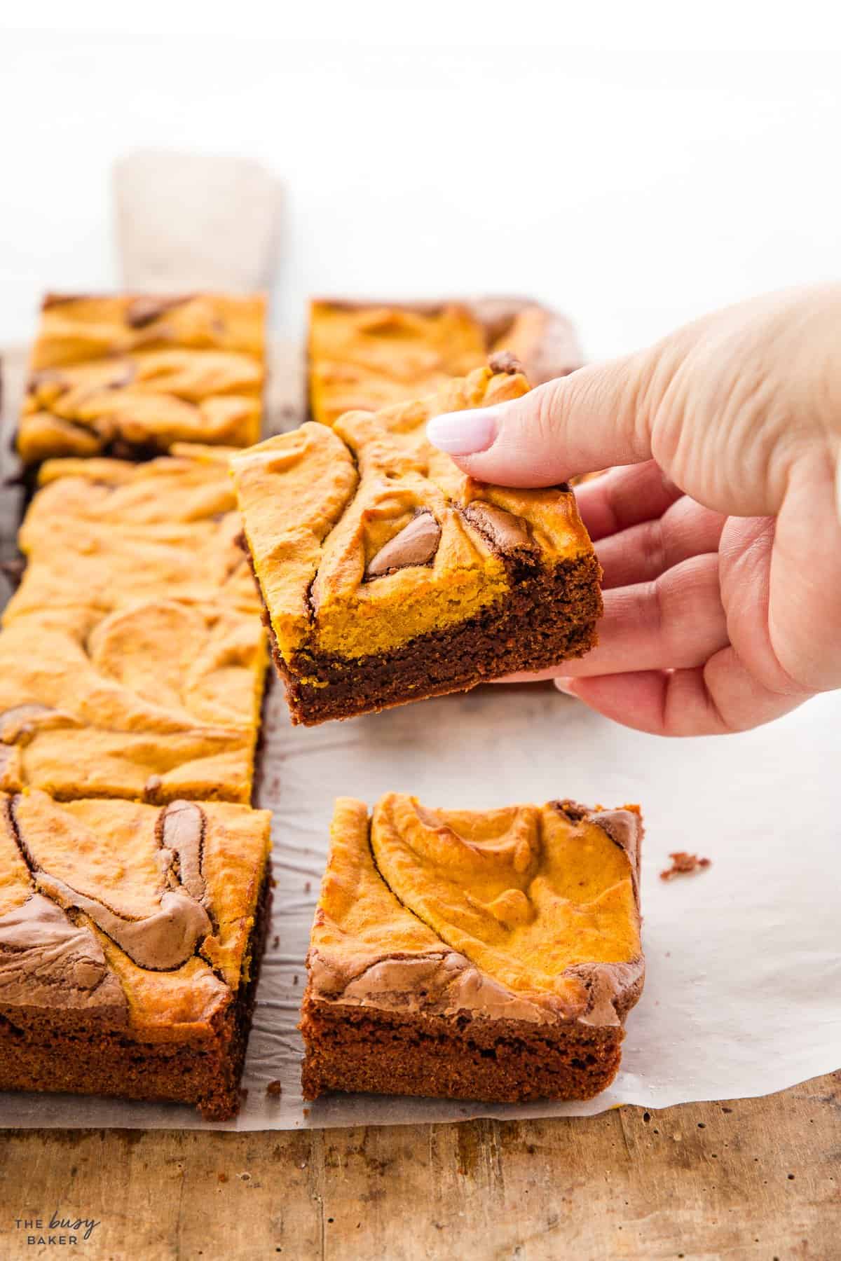 hand holding a brownie with pumpkin topping
