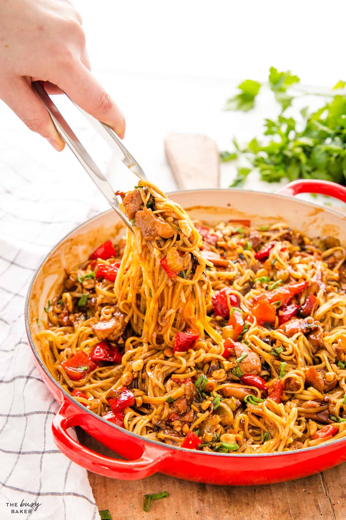 tongs serving kung pao chicken with rice noodles