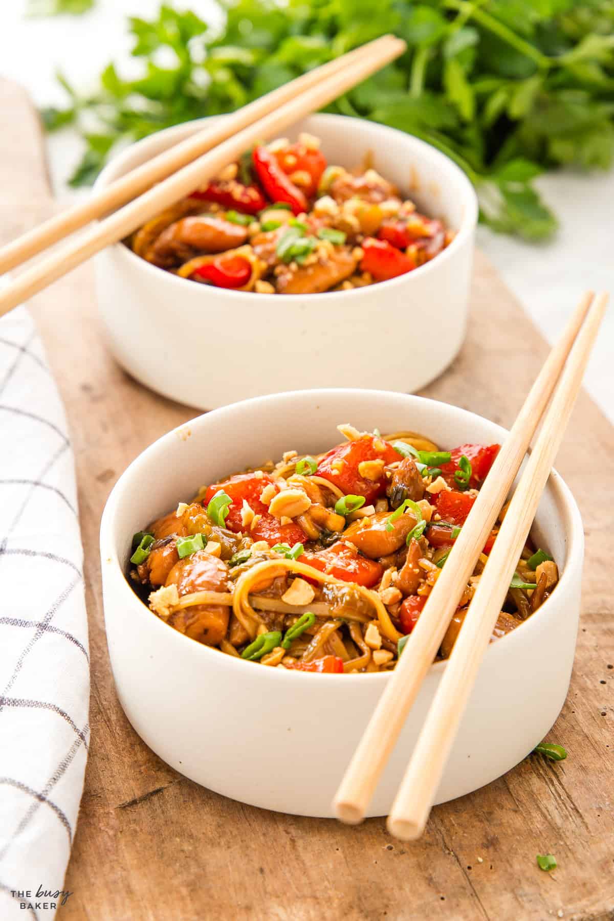 kung pao chicken in a white bowl with chopsticks