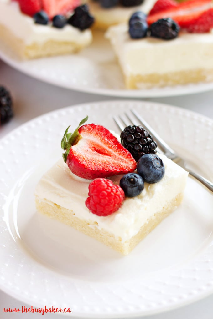 These Berry Cheesecake Sugar Cookie Bars make the perfect dessert for spring and summer featuring a cookie base, creamy cheesecake and fresh berries! Recipe from thebusybaker.ca!