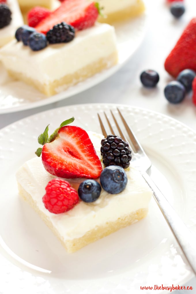 These Berry Cheesecake Sugar Cookie Bars make the perfect dessert for spring and summer featuring a cookie base, creamy cheesecake and fresh berries! Recipe from thebusybaker.ca!