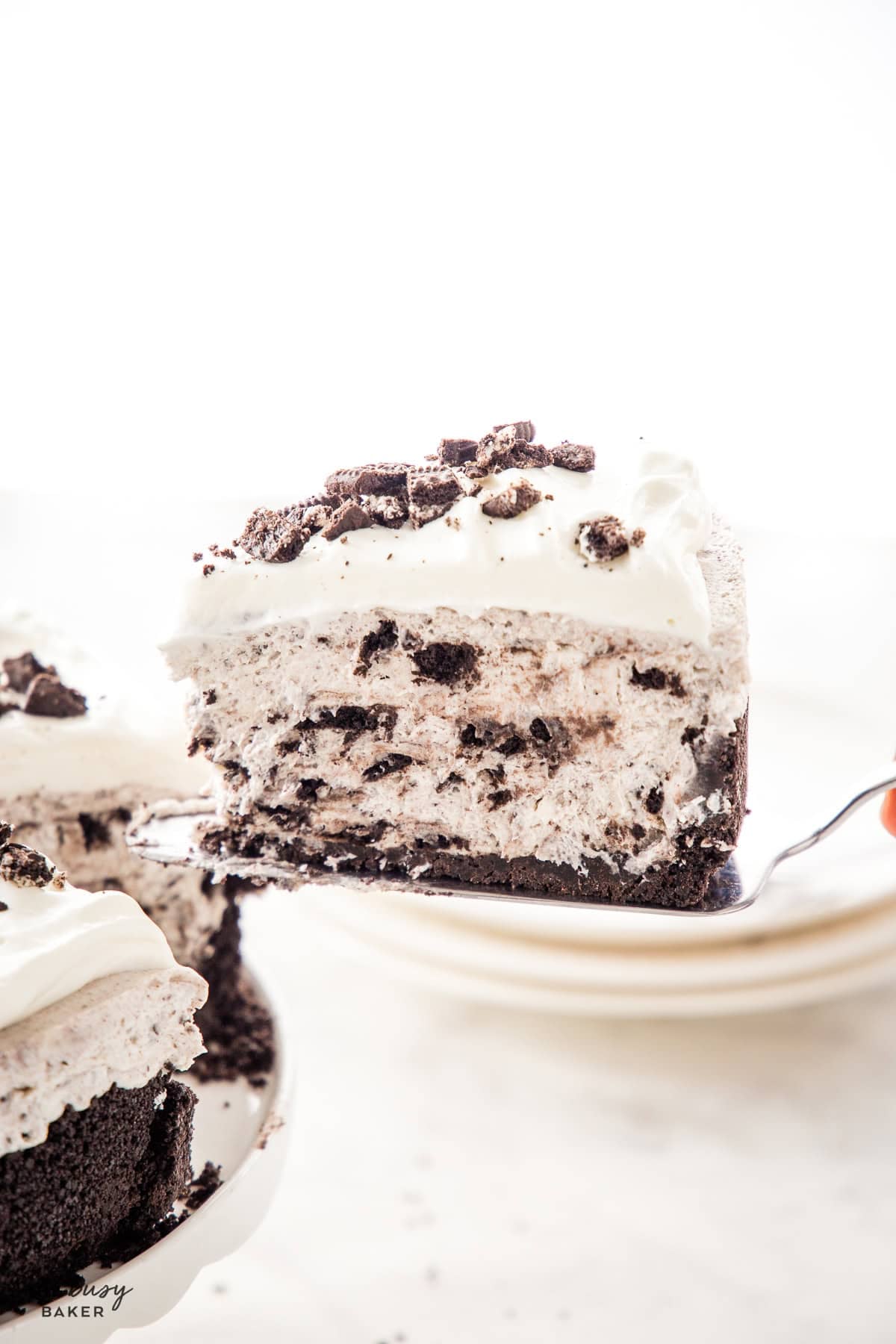 hand serving a slice of easy no bake oreo cheesecake