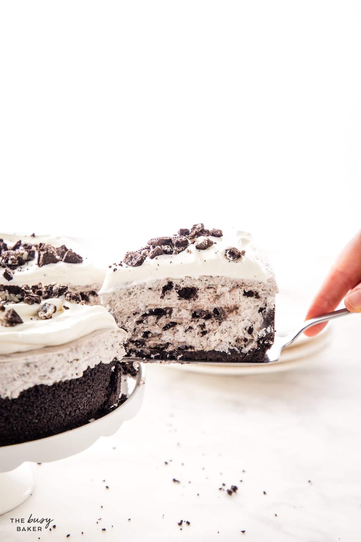 hand serving a slice of easy no bake oreo cheesecake