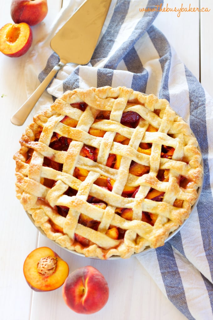 Overhead image of a lattice top over a fresh peach pie with a blue and white striped tea towel underneath