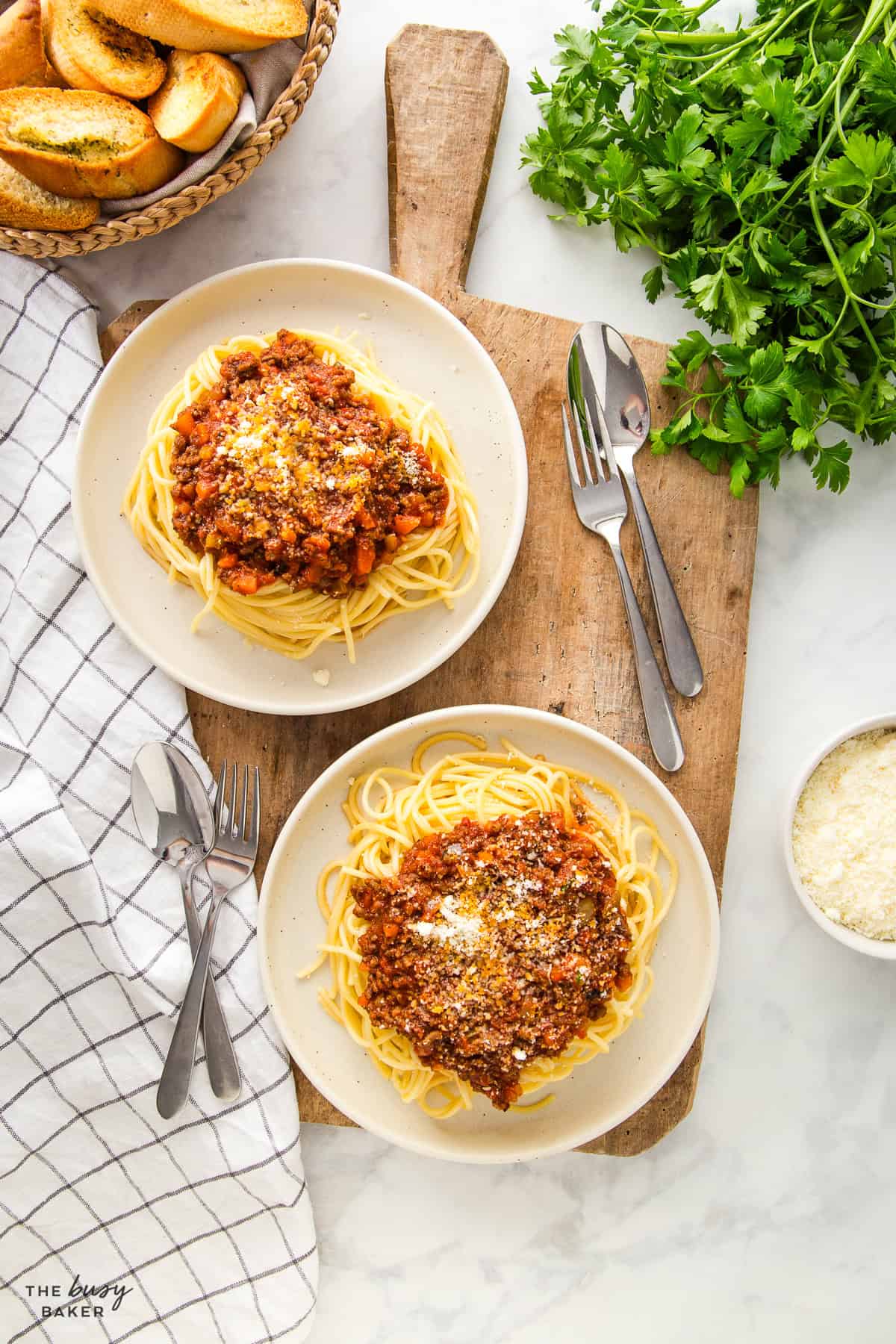 2 plates of spaghetti and meat sauce with parmesan cheese