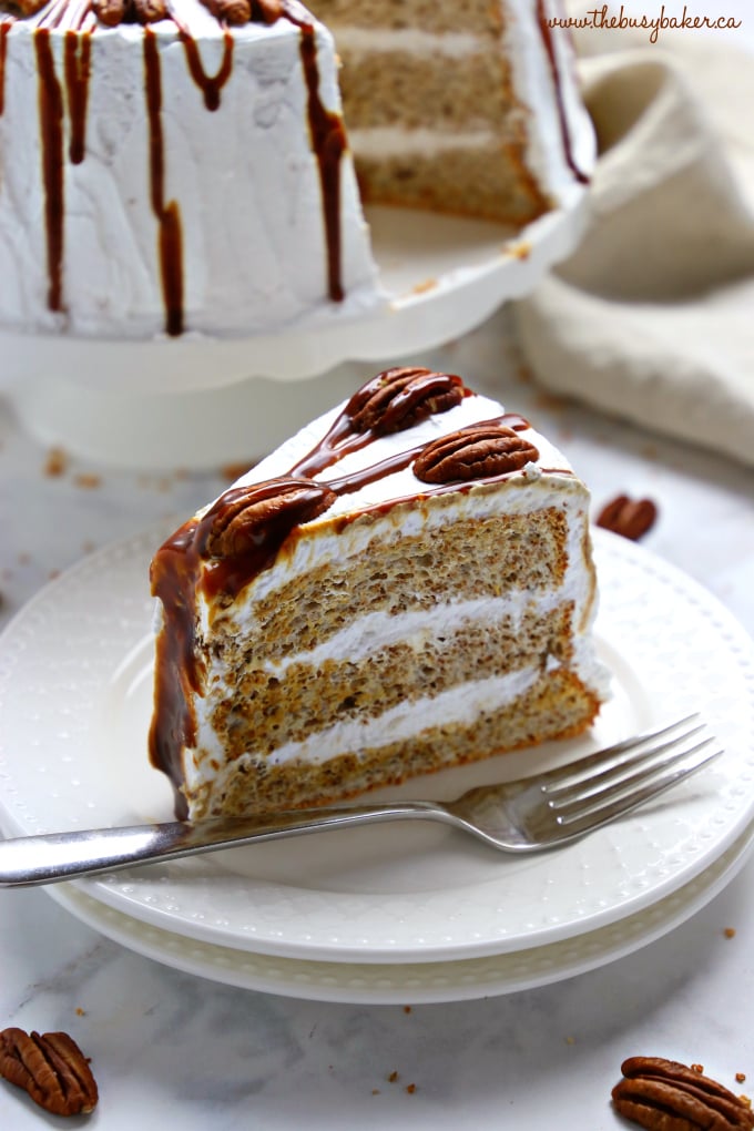 This Classic Caramel Pecan Schmoo Torte is a delicious and classically Canadian layer cake with a pecan-flavoured Angel Food Cake base, fluffy whipped cream frosting, and homemade caramel sauce! It's sweet and decadent and makes the perfect impressive dessert! Recipe from thebusybaker.ca! #schmootorte #canadiancake #caramelpecancake