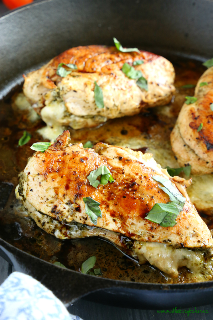 Skillet Pesto Caprese Stuffed Chicken with basil and mozzarella cheese in cast iron skillet