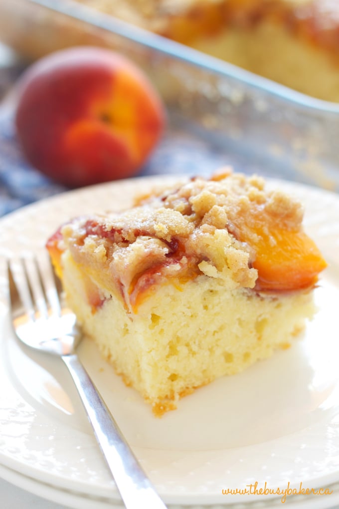 Peach Streusel Cake on white plate with fresh peach