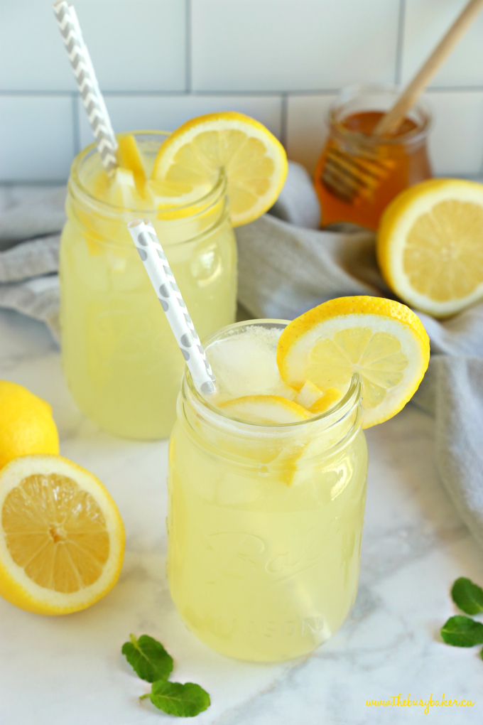 homemade healthy lemonade in mason jars with lemon slices and grey paper straws