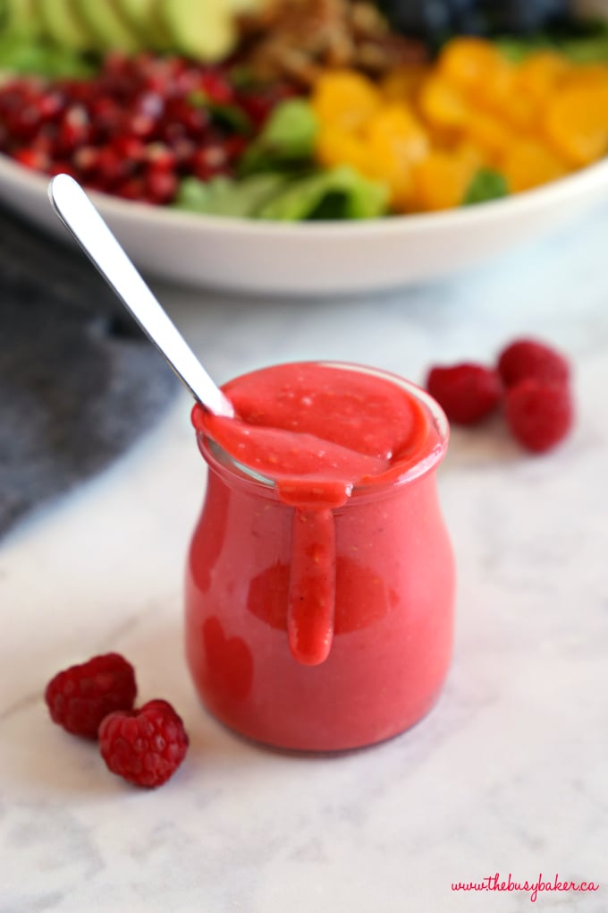 raspberry vinaigrette dressing with spoon and fresh salad