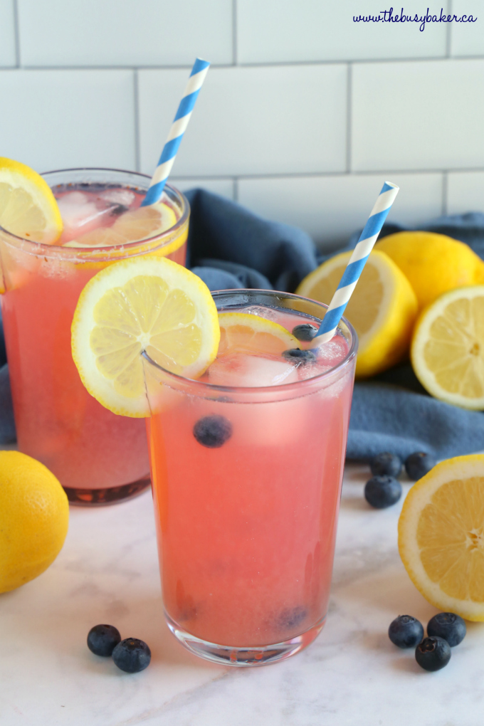Healthy Blueberry Lemonade with lemon slice and paper straw, with fresh blueberries and lemons