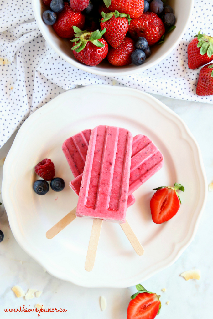 Healthy Berry Coconut Popsicles on plate with fresh berries and toasted coconut