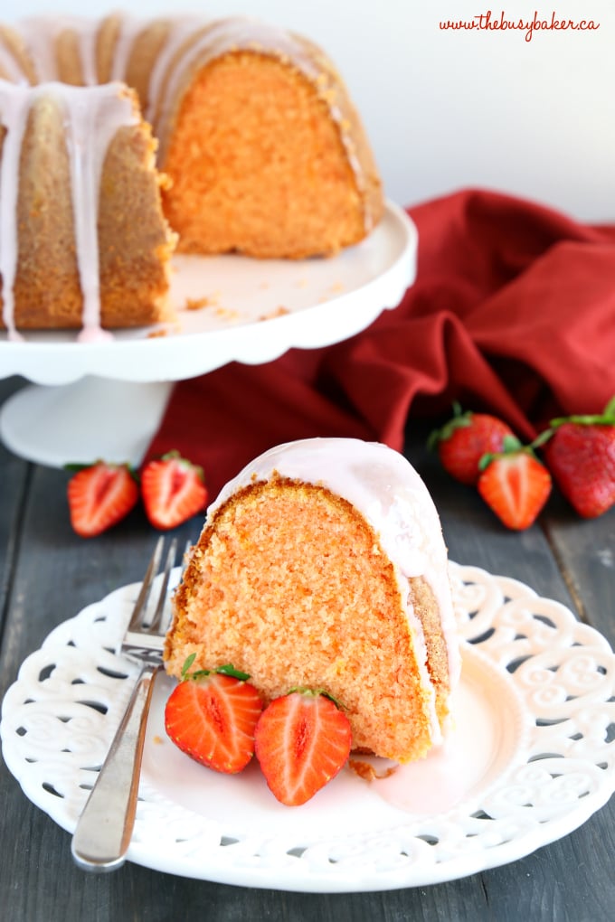 Best Ever Strawberry Pudding Cake with strawberry glaze on white lace plate