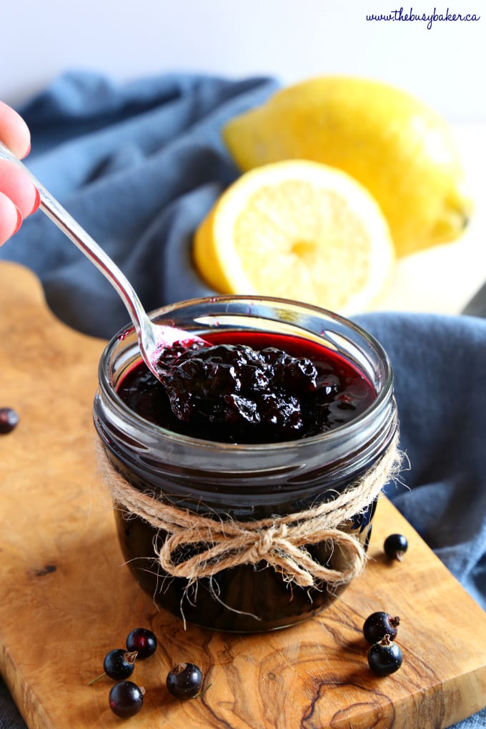 Best Ever Black Currant Jam with spoon and olive wood board