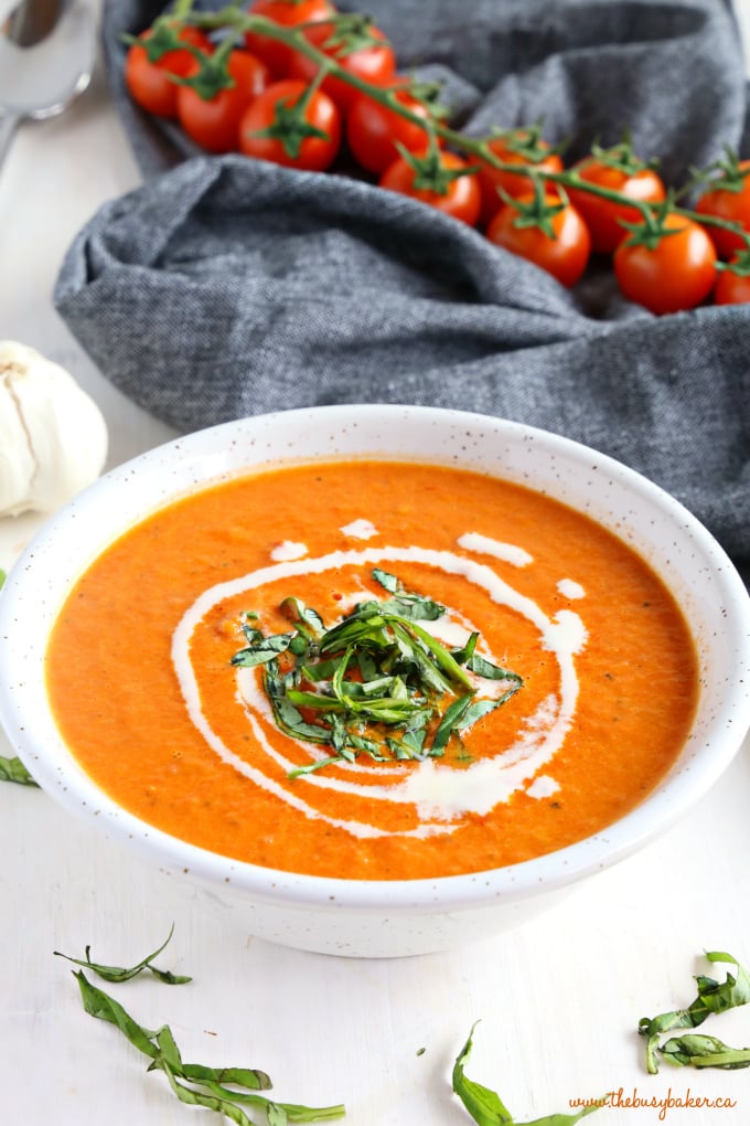 Easy Homemade Roasted Tomato Soup in white bowl with tomatoes and basil
