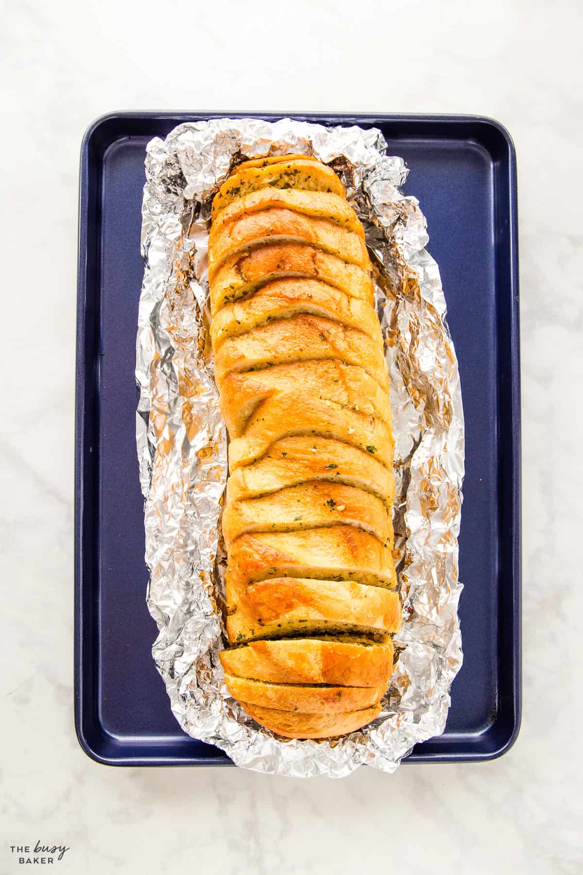 overhead image: garlic bread in foil on a baking pan