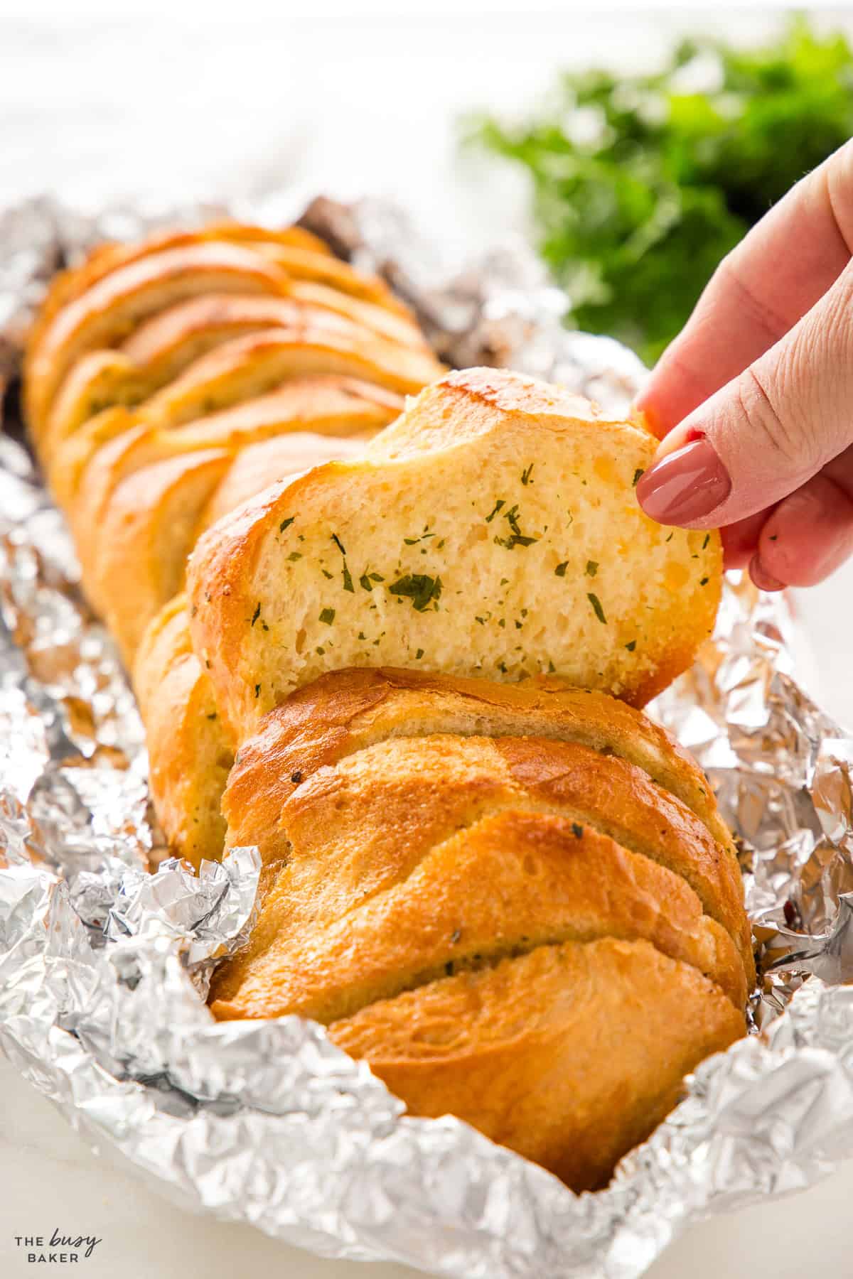 hand reaching for a piece of garlic bread